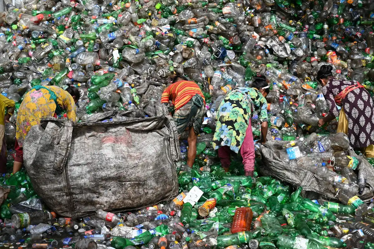 Arbeiter sortieren Abfälle auf einer Halde mit Recycling-Maschinen im Hintergrund
