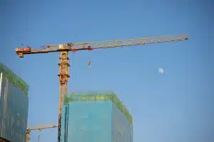 Unvollendetes modernes Hochhaus mit Baukränen und Gerüsten vor grauem Himmel