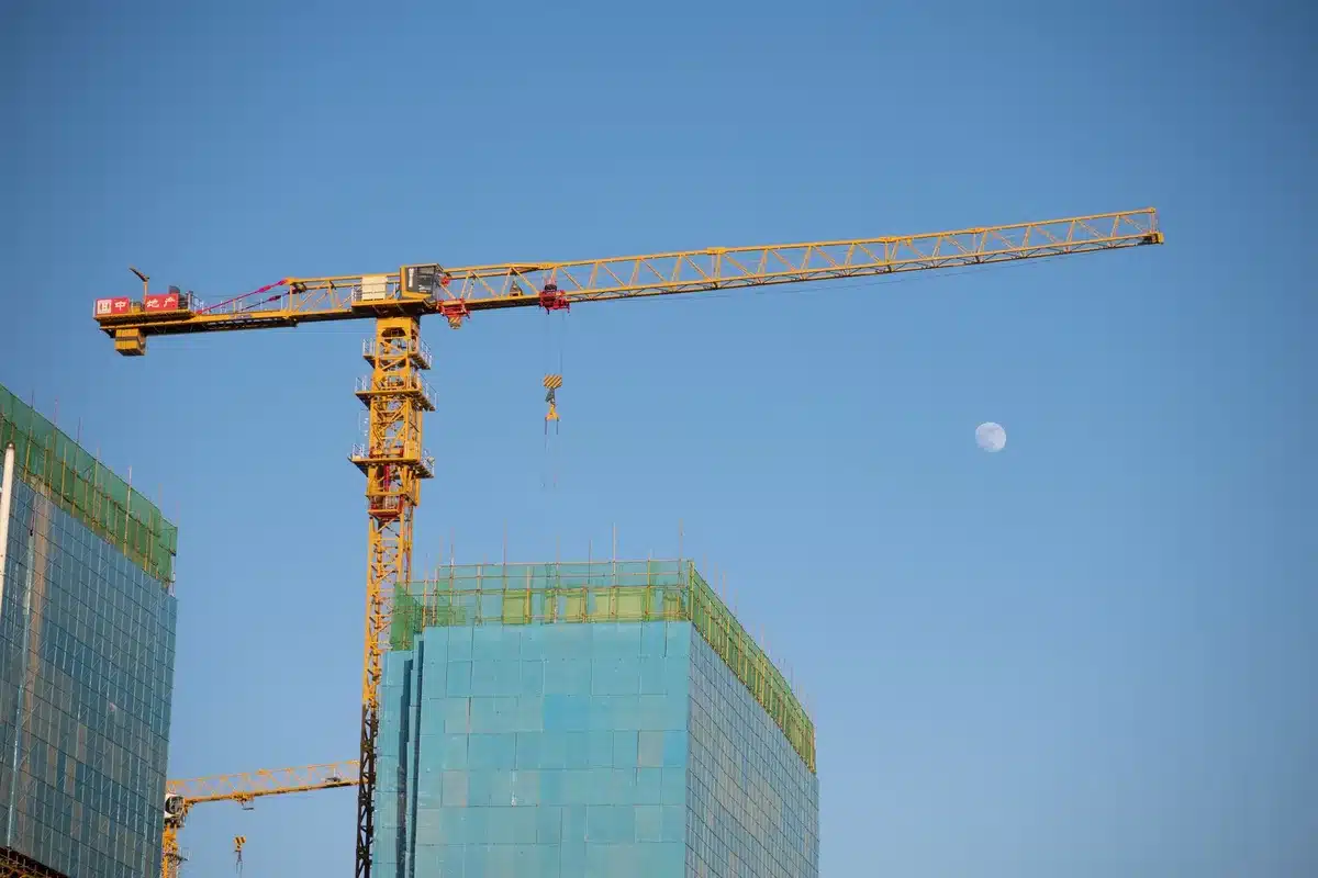 Unvollendetes modernes Hochhaus mit Baukränen und Gerüsten vor grauem Himmel