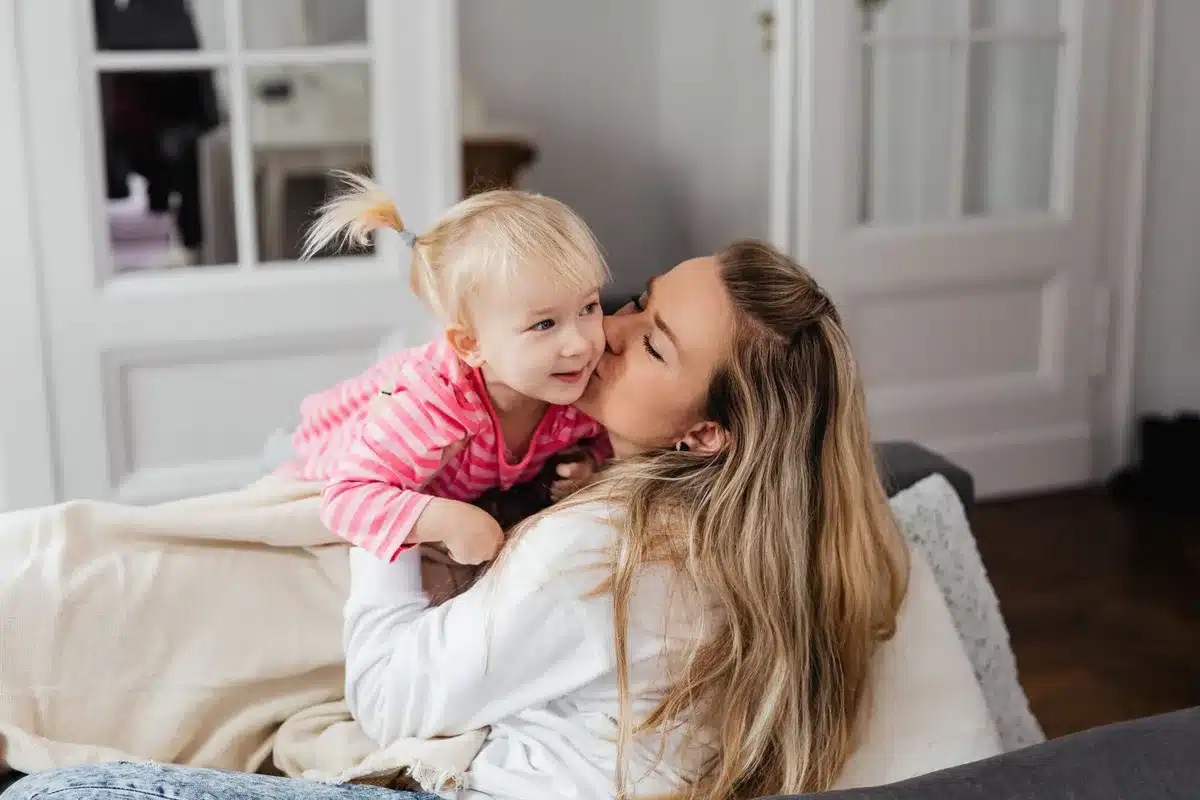 Mutter und Tochter sitzen zusammen auf einem Sofa in einem gemütlichen Wohnzimmer mit Kaffee und Snacks.