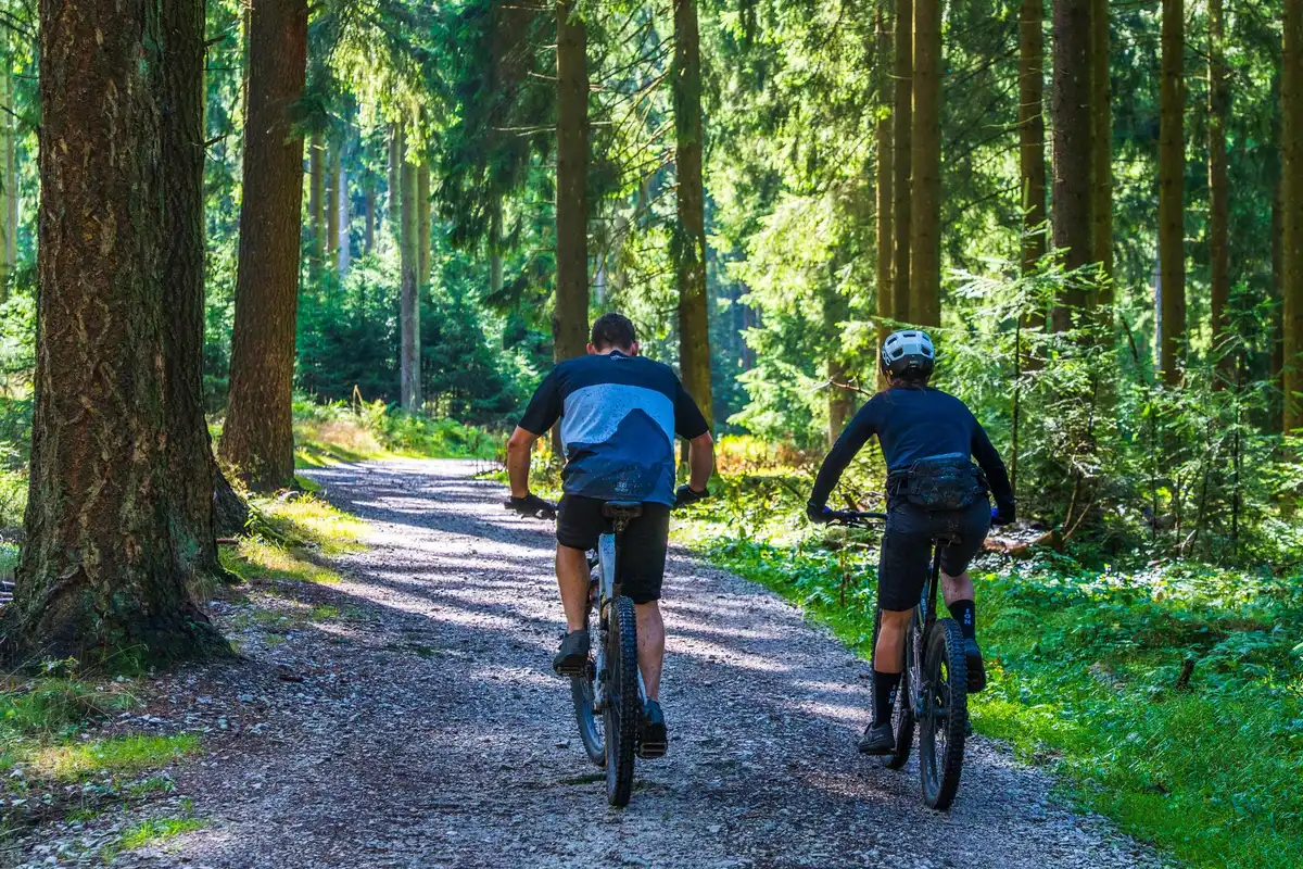 Radfahrer auf einem Schotterweg durch eine hügelige Landschaft mit Bergen am Horizont