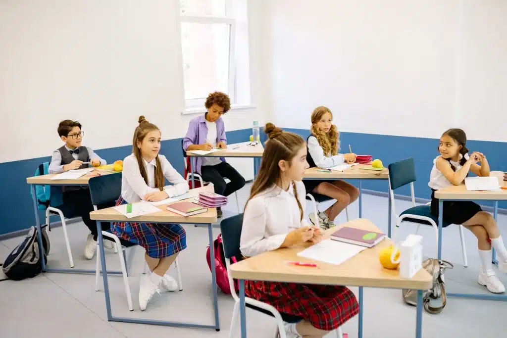 Grundschulklassenzimmer mit Schülern beim Lernen und Lehrkraft bei individueller Unterstützung